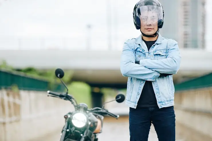 Asiatisk mann i en motorsykkelhjelm som står utendørs