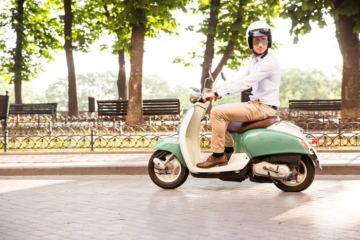 En trendy mann som kjører en elektrisk scooter